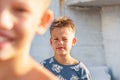 Winking boy stands behind defocused elder brother on beach Royalty Free Stock Photo