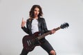 Cool woman guitarist making a rock and roll hand sign Royalty Free Stock Photo