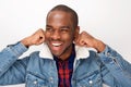 Cool young african american male fashion model smiling with denim jacket against white wall Royalty Free Stock Photo