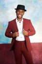Cool young african american male fashion model smiling with hat and vintage suit by wall Royalty Free Stock Photo