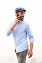 Cool young arabic man smiling and talking on cellphone against white background