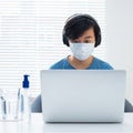 Cool young Asian boy doing homework on laptop computer Royalty Free Stock Photo