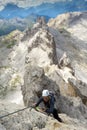 Cool young attractive mountain climber checks her mobile phone while climbing a Via Ferrata in the Dolomites