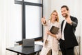 Cool. Young beautiful team of man and woman is using digital tablet while standing at the office. They holding tablet in Royalty Free Stock Photo