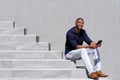 Cool young black guy sitting on steps using digital tablet Royalty Free Stock Photo