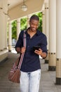 Cool young black guy walking outside with mobile phone and bag Royalty Free Stock Photo