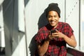 Cool young black man holding cellphone and smiling Royalty Free Stock Photo