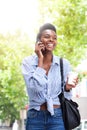 Cool young black woman walking and talking on mobile phone Royalty Free Stock Photo