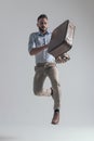 Cool young fashion model leaping up while holding jacket and briefcase Royalty Free Stock Photo