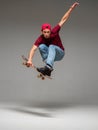 Cool young guy skateboarder jumps on skateboard in studio on gray background. Photography about skateboarding tricks Royalty Free Stock Photo