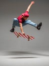 Cool young guy skateboarder jumps on skateboard in studio on grey background. Photography about skateboarding tricks Royalty Free Stock Photo
