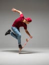 Cool young guy skateboarder stands on skateboard in studio isolated on gray background. Skateboarding tricks Royalty Free Stock Photo