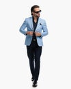 cool young man with sunglasses looking to side and buttoning blue suiti jacket Royalty Free Stock Photo