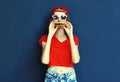 Cool young woman eating burger wearing baseball cap, sunglasses over blue wall Royalty Free Stock Photo