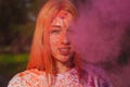 Cool young woman posing in a cloud of pink dry powder, celebrating Holi colors festival Royalty Free Stock Photo