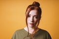 Cool young woman with red hair messy bun hairstyle and loose strands