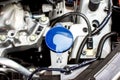 Coolant reservoir tank with blue cap inside car engine bay Royalty Free Stock Photo