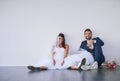 The coolest bride and groom ever. Studio shot of a newly married young couple sitting together on the floor against a