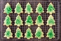 Cooling rack filled with baked Christmas Tree cookies on wood table
