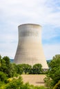 The cooling tower of a nuclear power plant releasing vapor next to a plowed field