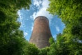 Cooling Tower Surrounded by Lush Green Trees Under a Bright Blue Sky with Clouds Royalty Free Stock Photo