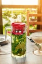 Cooling vitamin detox drink made from crushed mint leaves and currants in a large transparent glass jar with red lid is