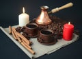 Cooper Turkish coffee pot, two cups of coffee, white and red candles, coffee beans, cinnamon sticks, star anise, canvas napkin Royalty Free Stock Photo