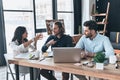 Cooperation in action. Group of young modern people in smart casual wear working together while sitting in the office Royalty Free Stock Photo