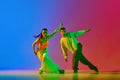 Coordinated movements. Young man and woman, street dancers in motion, dancing hip hop against blue red background in Royalty Free Stock Photo