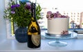 Birthdag cake decorated with pink flowers and a bottle of vintage French champagne Don Perignon