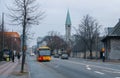 Yellow bus driving on Enghavevej street on a cloudy winter day.