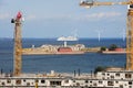 Construction and tower cranes against the background of the Trekroner fortress, wind turbines and liner Royalty Free Stock Photo