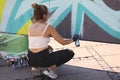Female street artist painting colorful graffiti on wall - Modern art concept with urban girl painting live murales with aerosol co