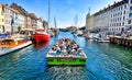 Tourist excursion boat travels on the canal in the Nyhavn in Copenhagen Denmark