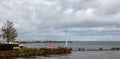 Gray and storm clouds overlooking a marina left and a distant wind farm Royalty Free Stock Photo