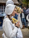 Teenage lady in traditional Danish costume holding up a venetian mask