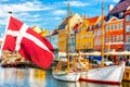 Copenhagen iconic view. Famous old Nyhavn port in the center of Copenhagen, Denmark during summer sunny day with Denmark flag on