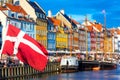 Copenhagen iconic view. Famous old Nyhavn port in the center of Copenhagen, Denmark during summer sunny day with Denmark flag on Royalty Free Stock Photo