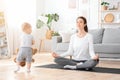 Coping With Motherhood. Relaxed Mom Meditating With Cute Toddler Baby Around