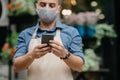 Copped portrait of modern florist in apron and protective mask, and online delivery of bouquets during COVID-19 pandemic Royalty Free Stock Photo