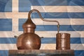 Copper alambik on the background of the national flag of Greece. Winemaking and distillery.