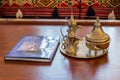 Copper antique Arabian tea pot and a travel guide book with background of Arabian traditional sofa