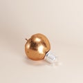 Copper apple light bulb on pale pink background