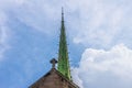 Copper art deco church spire and Celtic cross on top of church against beautiful cloudy blue sky Royalty Free Stock Photo