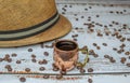 Copper cup with espresso on white wooden table with organic coffee beans with Cuban hat in the background