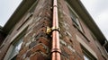 Copper Downpipe With A Brass Bracket On A Brick Wall, generative ai Royalty Free Stock Photo