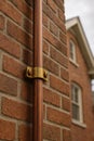 Copper Downpipe With A Brass Bracket On A Brick Wall, generative ai Royalty Free Stock Photo