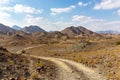 Copper Hike trail, winding gravel dirt road through Wadi Ghargur riverbed and rocky limestone Hajar Mountains in Hatta, UAE Royalty Free Stock Photo