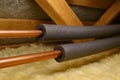 Copper pipe insulation in attic for effective temperature control and energy efficiency. concept of home improvement, thermal Royalty Free Stock Photo