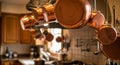Copper pots and pans hang from a ceiling rack in a cozy kitchen. The warm, reflective Royalty Free Stock Photo